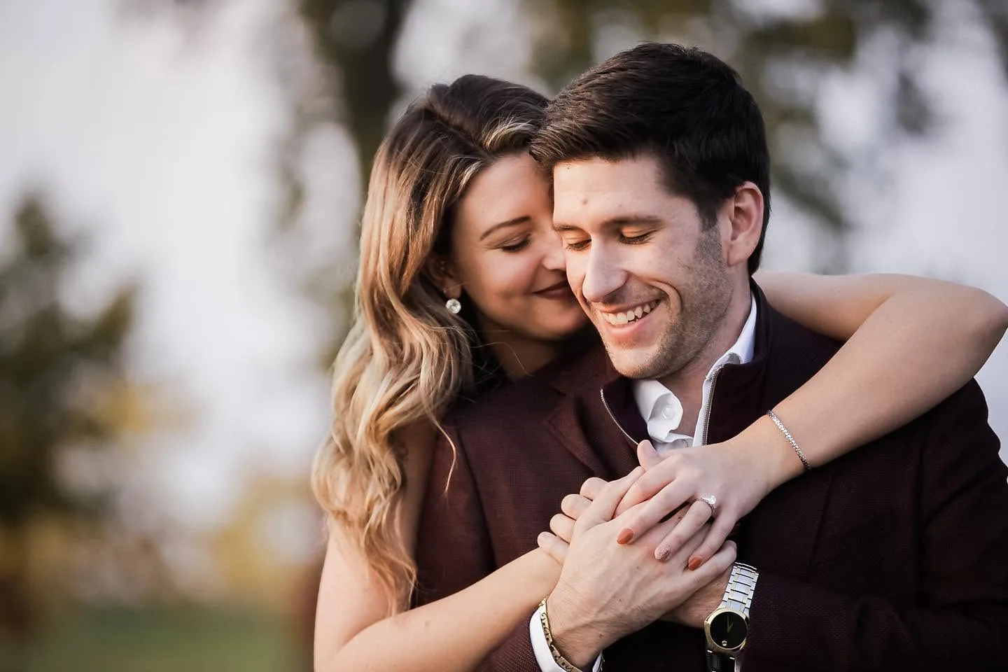 Chris and Tina embracing outdoors in Windsor, her Joseph-Anthony engagement ring on the hand resting over his